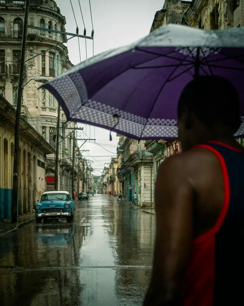 FOTOGRAFIE TIPPS: 10 FOTOGRAFEN VERRATEN IHRE TRICKS, UM SOFORT BESSERE FOTOS ZU MACHEN 6 Fotografie Tipps - Jörg Nicht - Kuba -Person auf der Straße mit Regenschirm - Auto
